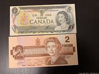 Front and back of the Canadian one dollar bill showing Queen Elizabeth II and Parliament buildings.