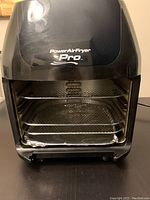 Front view of black Power Air Fryer Pro main unit with open cooking chamber and visible racks