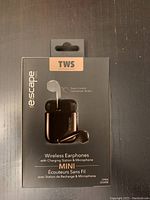 Front of sealed box showing Escape Mini wireless earphones with charging station, highlighting touch control and TWS technology.