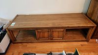Full view of the rectangular wooden coffee table showing two central doors and open shelves on sides.