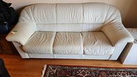 Full frontal view of off-white leather couch showing three-seat configuration and overall condition