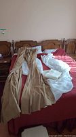 Four curtain panels laid over a bed, showing two beige curtains and two white sheers.
