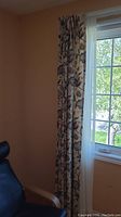 Floral patterned curtain panel hung on window next to sheer panel allowing light through.