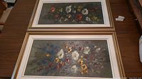 Photo of two framed and matted oil paintings with floral subjects, one with a gold frame and the other with a white frame.