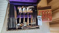Complete set of 1847 Rogers Brothers cutlery in a purple velvet lined box showing knives, spoons, a serving fork, and a butter knife along with a color printed insert.