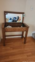 Full view of wooden table with drawer opened revealing contents, mirror attached to the back.