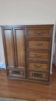 Full frontal view of vintage wood dresser showing a tall cabinet door on the left and five drawers on the right, some drawer handles visible with one missing on bottom drawer.
