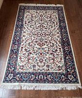 Full top-down view of the ornate area rug showing intricate multi-colored floral and geometric design with a navy blue border and cream central field.