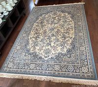 Full frontal view of rectangular area rug laid flat on wood floor displaying complete pattern and fringe intact