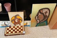 Two paintings and chess board displayed on floor