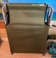 Folded green camping cot, showing fabric and metal frame sides