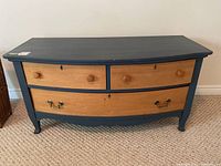 Main frontal view of wood dresser showing two small upper drawers with wooden knobs and one larger lower drawer with metal handles. Blue painted frame and natural wood drawer fronts.