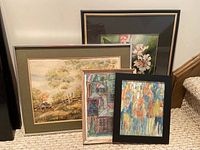 Four framed original artworks, three with glass, one without, leaning against wall near stairs