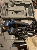 Ryobi corded hand planer with black and blue handle, orange controls, and attached power cord, set inside gray molded plastic carrying case.
