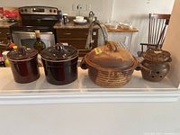 Pottery casserole, garlic keeper, and two crocks displayed on a kitchen counter showing overall lot contents