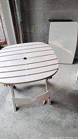 White slatted round-edged square folding table with tan legs.