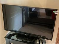 Full front view of LG 47-inch flat screen TV on stand with two remotes placed in front.