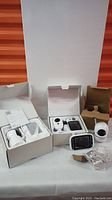 Three boxed baby monitor units shown with cameras and handheld screens, accessories, and packaging.