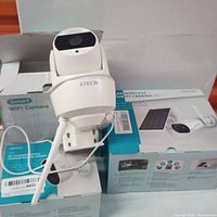 Three white solar wireless security cameras shown with antennas and mounting brackets, displayed on their original blue and white packaging boxes.
