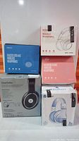 Five boxes of wireless headphones stacked, showing variety of brands and packaging designs.