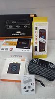 Full lot showing packaging for HDMI KVM switch, EvBox Plus Android TV box, Air Fly Mouse, and 1Mii wireless AV transmitter, plus a mini visual of the keyboard controller.