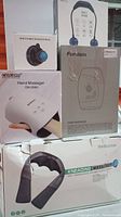 Photo of five boxed body massagers including hand massagers, neck fan, mountable massage ball