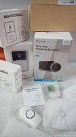 Overview of the lot showing EZVIZ wire-free peephole doorbell CP4 box, two mini wireless doorbells, user manual, batteries, mounting screws, and packaging boxes.