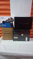Four boxed massage guns: Renpho R3 Mini, Aerlang, two Wattne
