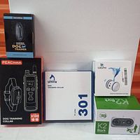 Front view of all five boxed items: two dog training collars, an ultrasonic dog trainer, cat interactive toy, and K2 Back device.