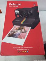 Red box of Polaroid Now+ connected i-Type instant camera, highlighting lens filter kit included, showing five filter color icons on packaging.