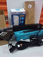 Overview of power outlet lot including Bell+Howell Swivel Power bar in box, black power bars, extension cord and power adapter cords.