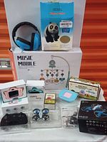 Wide view of all items showing mini drone, kids cameras, music mobile, panda toy, remote, and accessory boxes in factory packaging