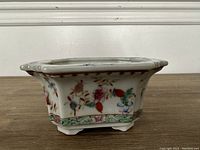 Side view showing colorful floral and butterfly hand painted designs on the ceramic jardiniere.