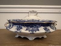 Side view of Wedgwood blue and white tureen with lid, showing handles and decorative blue floral pattern with gold accents.