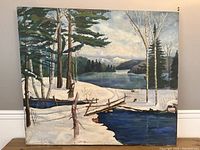 Front view of the landscape oil painting showing snow, trees, water, and mountains with visible wear and tears.