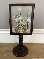 Full view of the antique painting on glass displayed on a dark wooden pedestal stand.