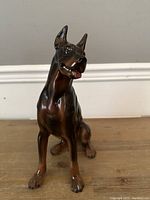 Front view of glossy porcelain Doberman figurine with detailed facial features and posture.