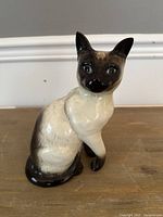 Side view of Beswick ceramic Siamese cat figurine showing the cream body and dark brown face, paws, and tail with glossy finish.