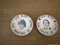 Photo showing the front of two small tea bag plates with portraits of Princess Diana and Prince Charles along with inscriptions around the border.