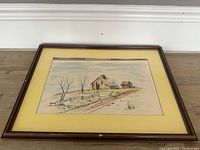 Framed lithograph print showing rustic barn and landscape with bare trees, yellow mat and dark brown frame