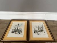 Two framed British cityscape prints side by side on floor against wall