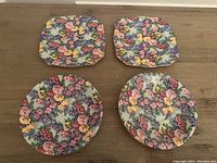 Four plates arranged with two square plates on top and two round plates below showing floral chintz pattern.