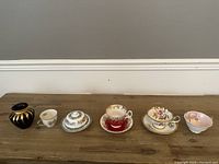 All six porcelain items displayed in a row on wooden surface against grey wall