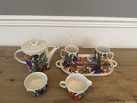 Full view of all tea set items displayed together including teapot, two mugs on tray, creamer, and sugar bowl.