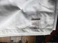 Folded white percale sheet with visible care label showing brand and fabric details.