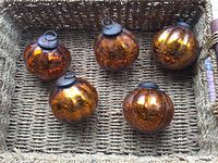 Photo of five crackled copper glass melon-shaped ornaments with metal tops and hangers arranged in a basket (basket not included).