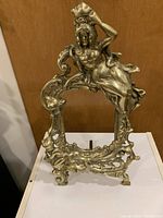 Full view of ornate brass picture frame with cherub on the top right corner, showing decorative details and open picture opening.