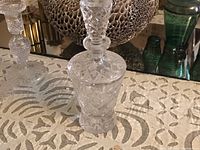 Photo of a clear lead crystal decanter featuring multiple facets on the body and stopper placed on a reflective surface.