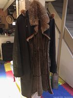 Front and inside view of Danier shearling coat showing dark brown leather and tan shearling lining, hood with fur trim visible