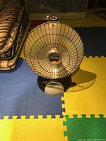 Photo of a single compact black and white heat lamp heater with grill and heating element visible.